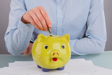 Business womans hand puts coin in piggy bank. Save money and financial investment concept.