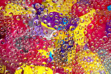Motley drops of water fall down against the background of the colorful glass mosaic. Close-up.