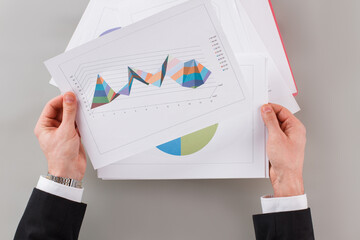 Businessman reviewing data in financial charts and graphs. Male hands holding documents with...