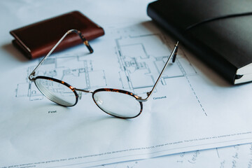 Glasses resting on floorplans in an office.