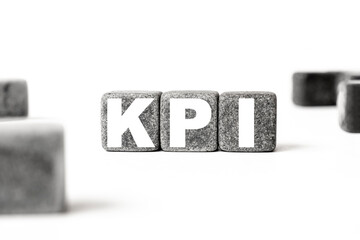 three stone cubes inscribed with the word KPI Key performance indicator among the cubes on a white background. Strong business concept