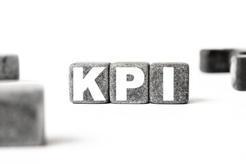 three stone cubes inscribed with the word KPI Key performance indicator among the cubes on a white...