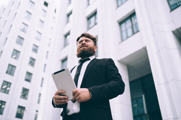 Fototapeta premium Respectable businessman in formal suit with tablet near business center