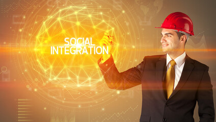 Handsome businessman with helmet drawing SOCIAL INTEGRATION inscription, social construction concept