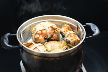 steamed crabs in pot, black background. Traditional Chinese cuisine