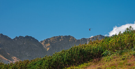 TOPR mountain rescue helicopter heading towards rocky summits to help tourists injured during climbing