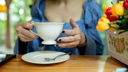Asian woman relaxing on couch with coffee at home in the living room