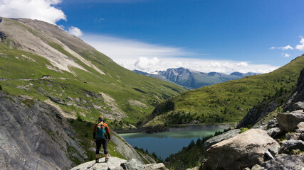 Hiker on one of the best pristine hiking trails in Austria with glacier and crystal blue lake on the background