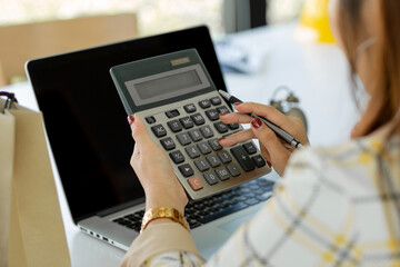 Businesswoman Young woman using calculator. with laptop computer,business, finance, saving, banking, and e-commerce, internet spending money, working from home concept.