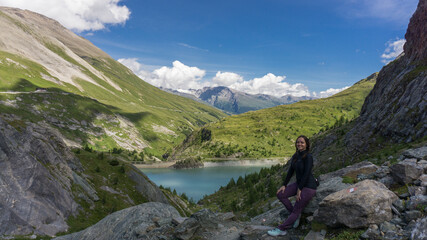 Fototapeta na wymiar Girl on one of the Europe top 10 best hiking trails with crystal clear blue sky and lake