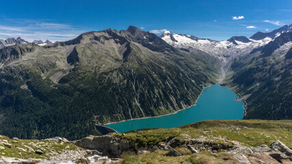 Obraz premium Panorama Alpine lake with dam in stunning mountain range