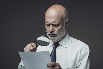 Businessman checking a document with a magnifier