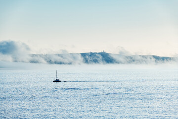 A lonely boat sails away from Ons Island in the Ria de Pontevedra in Galicia at dusk.