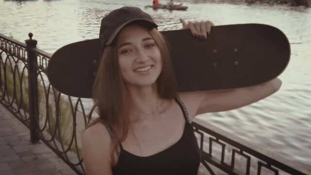 Young girl looks happy with her skateboard on her shoulder, vintage color