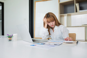 Young Business women are stressing about numbers with calculator and laptop at office ,a stress-to-work concept.
