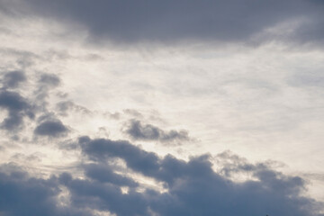 White light fluffy clouds in a blue sky with a solar flare.