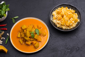 Curry or pumpkin soup with rice served in a ceramic platter on a black background - top view with writing space.