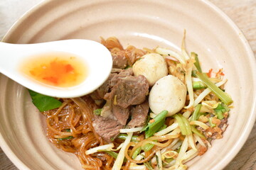 rice noodles topping braised pork and ball on bowl with bone in brown herb soup cup