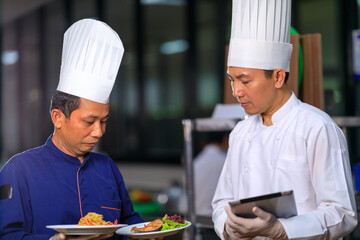 The male executive chef discussing the menu with his colleague in the kitchen.