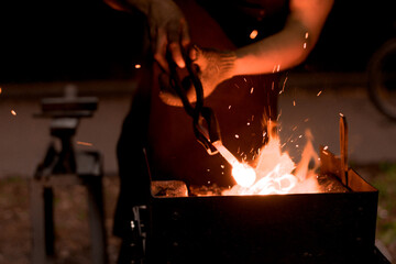 a furnace burning with a bright flame and the hands of a blacksmith with tongs. Fire of blacksmith...