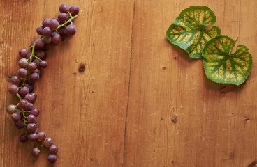 Red grapes and colorful grape leaves on a wooden vintage table.