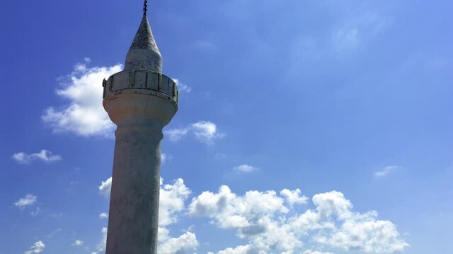 Old mosque near the sea side up the hill in Istanbul in the district of Anadolu Feneri, Third bridge in Istanbul, called Yavuz Sultan Selim bridge, is visible in the background. Blue sky with clouds.