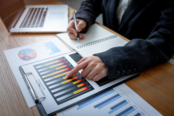 Financial Businesswomen analyze the graph of the company's performance to create profits and...