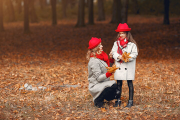 Fototapeta premium Fashionable mother with daughter. Family in a autumn park. Little girl in a red hat