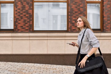 Young businesswoman walking talking on smartphone outdoor