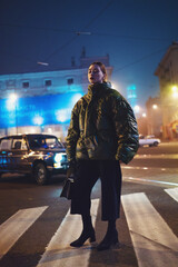 Urban woman standing on crosswalk at night in blue light