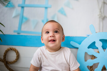 portrait of a happy baby in a white bodysuit on a wooden boat background