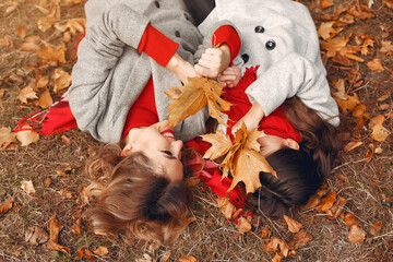 Fashionable mother with daughter. Family in a autumn park. Little girl in a gray coat