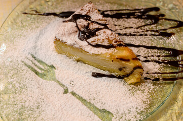 Piece of cheese cake with chocolate sauce and white sugar powder