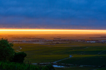 Amazing sunrise on rainy day over green grand cru vineyards near Epernay, region Champagne, France. Cultivation of white chardonnay wine grape on chalky soils of Cote des Blancs.