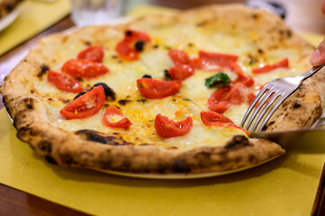 Eating of Italian pizza with mozzarella cheese, small red tomatoes and fresh basil
