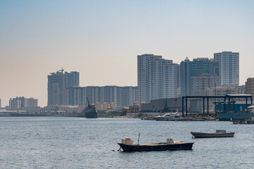 Fototapeta premium Empty fishing boats on the sea, waiting for its net catch during daytime in the Middle East with city building in the background