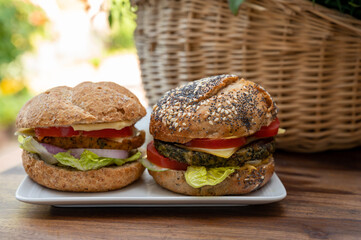 Eating of fresh and healthy vegetarian hamburgers with grilled spinach or pumpkin burgers, organic buns and vegetables
