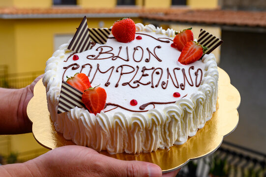Traditional white Italian birthday cake with congratilations, buon compleanno means happy birthday