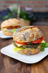Eating of fresh and healthy vegetarian hamburgers with grilled spinach or pumpkin burgers, organic buns and vegetables