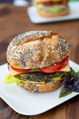 Eating of fresh and healthy vegetarian hamburgers with grilled spinach or pumpkin burgers, organic buns and vegetables