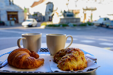 French breakfast in bakery served outdoor, cups of coffee and fresh baked croissants and pastry, morning food