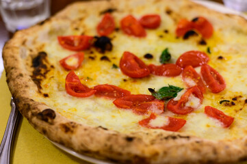 Eating of Italian pizza with mozzarella cheese, small red tomatoes and fresh basil
