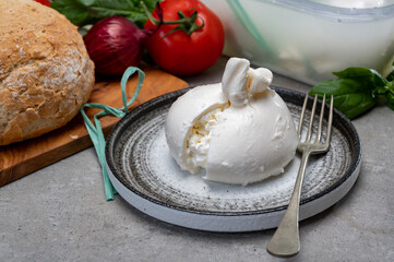 Eating of fresh handmade soft Italian cheese from Puglia, white balls of burrata or burratina...