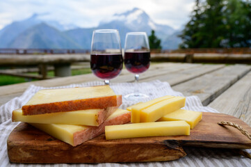 Cheese collection, French comte, beaufort or abondance cow milk cheese and glasses of red wine from...