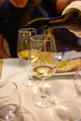Pouring in glass  cold dry white wine in outdoor cafe at night in Italy