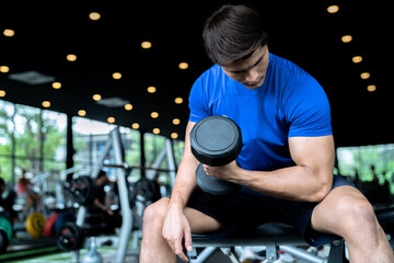 Fototapeta na wymiar Fitness Asian man lifting dumbbell in fitness gym.