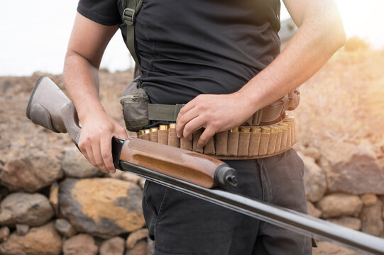 Close up of an unrecognizable hunter, loading shotgun, holds a shotgun and ammunition in his hand. High quality photo