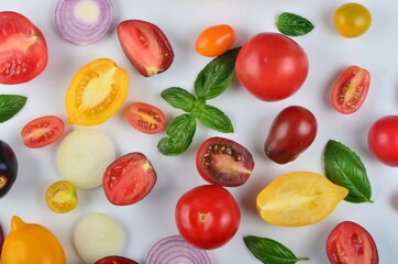 lots of tomatoes, onion slices and basil leaves isolated on a white background