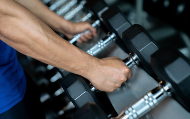 Naklejka na ściany i meble Hand holding dumbbell in the gym, Exercise and health care.