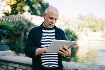 Fototapeta premium Concentrated senior man using tablet in park
